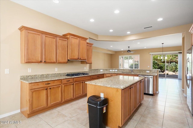 kitchen featuring stainless steel appliances, a kitchen island, pendant lighting, kitchen peninsula, and ceiling fan