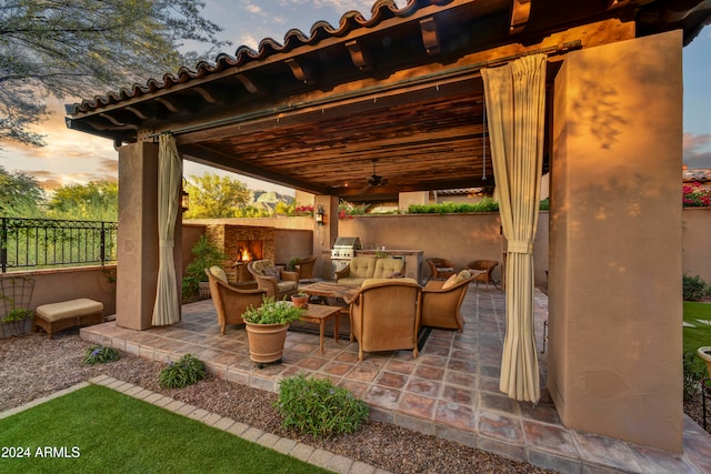 patio terrace at dusk featuring ceiling fan and grilling area