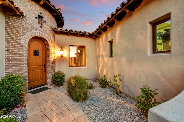 exterior entry at dusk featuring a patio