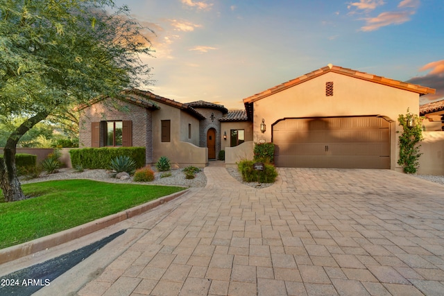 mediterranean / spanish-style home featuring a lawn and a garage