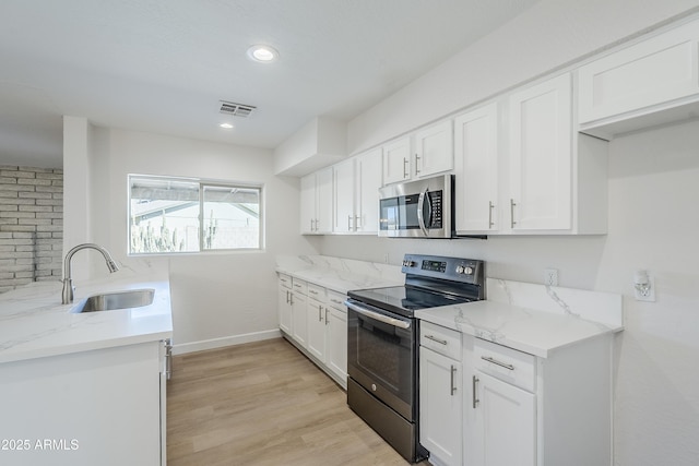 kitchen with light stone counters, sink, stainless steel appliances, and white cabinets