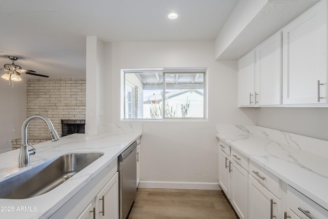 kitchen featuring sink, white cabinetry, light stone counters, light hardwood / wood-style floors, and stainless steel dishwasher