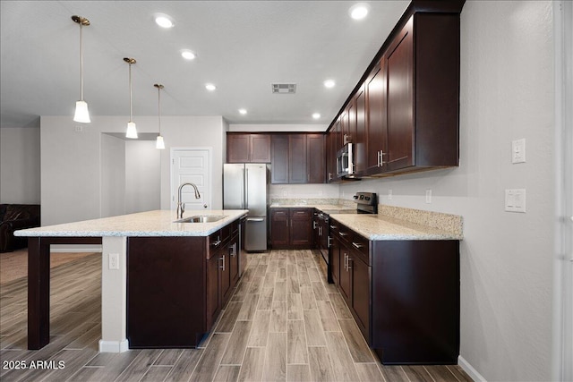 kitchen with visible vents, wood tiled floor, a sink, dark brown cabinetry, and appliances with stainless steel finishes