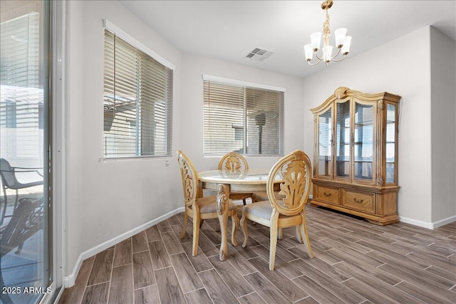 dining space with an inviting chandelier, baseboards, visible vents, and wood finish floors