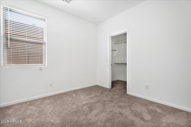 unfurnished bedroom featuring a closet, baseboards, a spacious closet, and carpet flooring