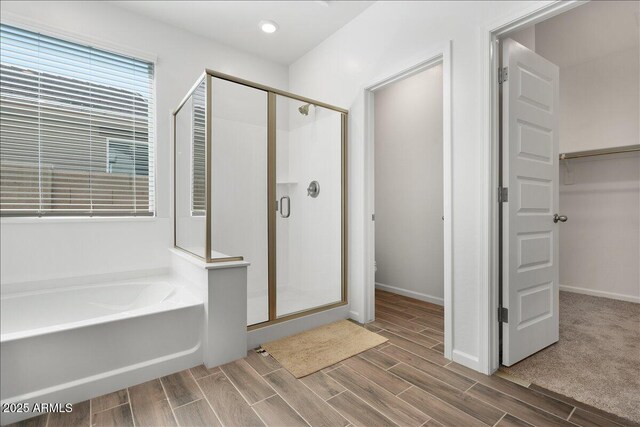 bathroom featuring a bath, a shower stall, a walk in closet, and wood tiled floor