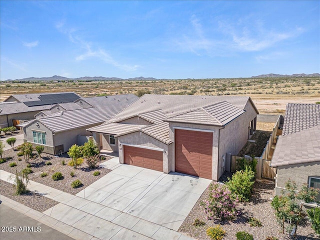 view of front of property featuring stucco siding, driveway, a tile roof, a mountain view, and an attached garage