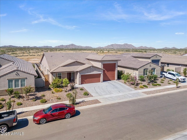 view of front of property with a residential view, concrete driveway, a garage, a tiled roof, and a mountain view