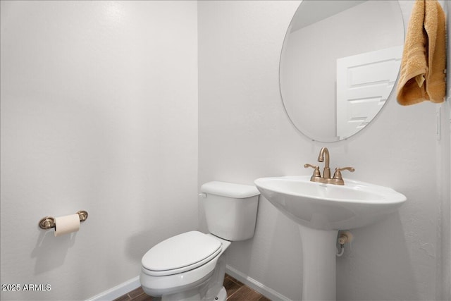 half bath featuring toilet, wood finished floors, and baseboards