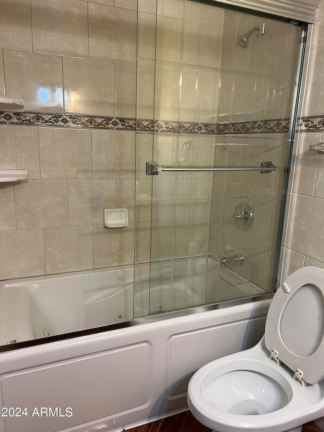 bathroom featuring combined bath / shower with glass door and toilet