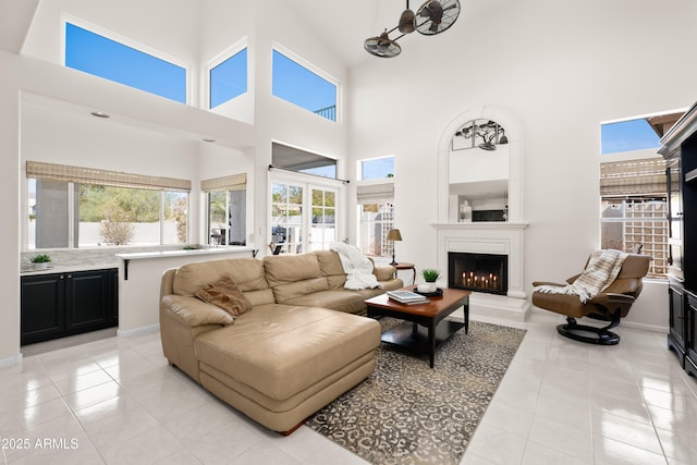 living room featuring light tile patterned flooring and a warm lit fireplace