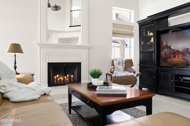 living area with light tile patterned floors and a warm lit fireplace