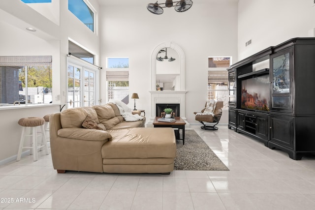 living room with baseboards, french doors, a fireplace, a towering ceiling, and light tile patterned flooring