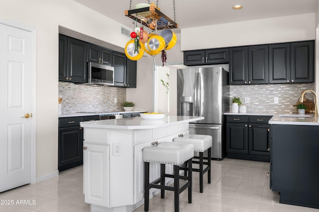 kitchen with a sink, appliances with stainless steel finishes, light tile patterned flooring, and light countertops