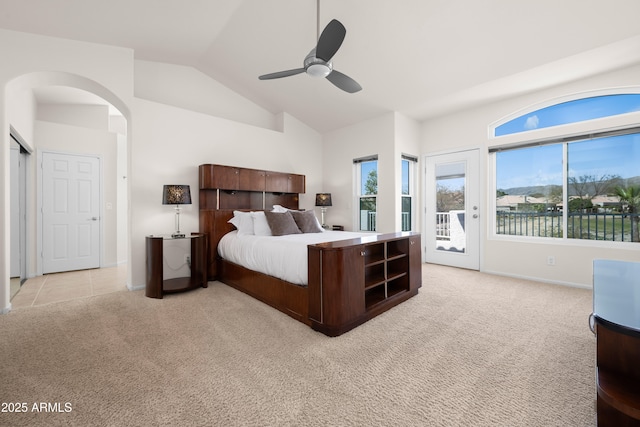 bedroom featuring ceiling fan, light colored carpet, lofted ceiling, arched walkways, and access to outside