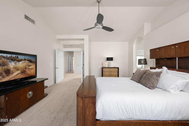 bedroom featuring visible vents, ceiling fan, light colored carpet, vaulted ceiling, and arched walkways