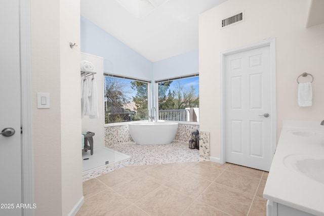 bathroom with visible vents, double vanity, tile patterned floors, a soaking tub, and a sink