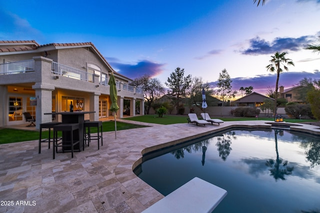 pool at dusk featuring a patio, fence, a fenced in pool, and an in ground hot tub