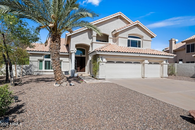 mediterranean / spanish home with stucco siding, a tile roof, driveway, and fence