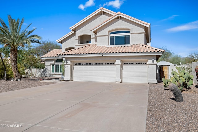 mediterranean / spanish home featuring a gate, stucco siding, concrete driveway, and fence