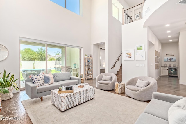 living room featuring wine cooler, a towering ceiling, and hardwood / wood-style floors