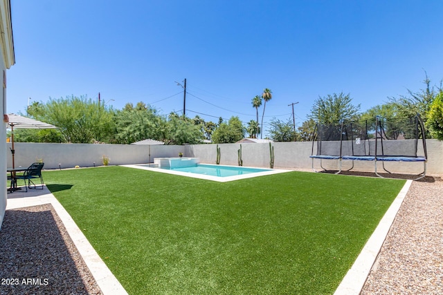 view of yard featuring a trampoline and a fenced in pool