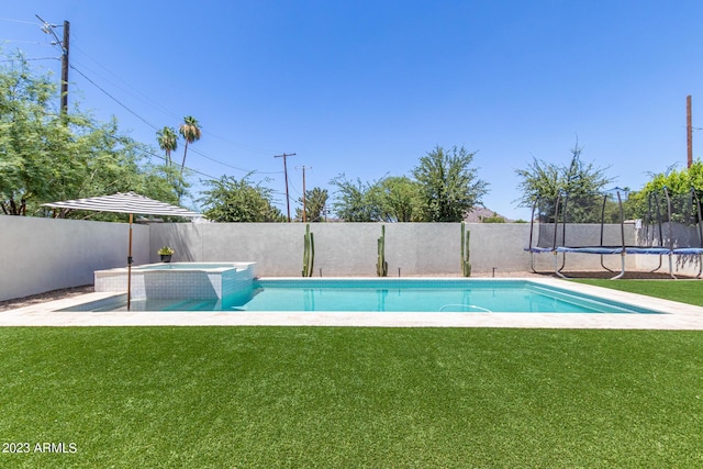 view of pool with an in ground hot tub, a yard, and a trampoline