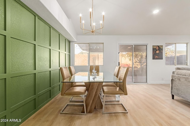 dining area with light hardwood / wood-style floors, a wealth of natural light, and an inviting chandelier