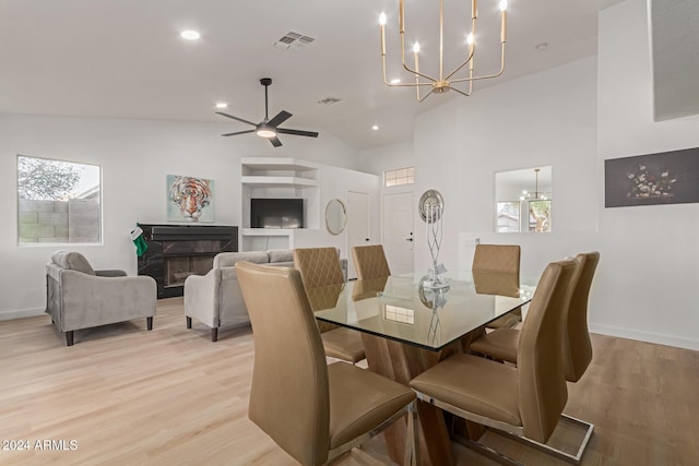 dining space with ceiling fan with notable chandelier, lofted ceiling, and light wood-type flooring