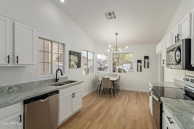 kitchen featuring appliances with stainless steel finishes, lofted ceiling, white cabinetry, and sink