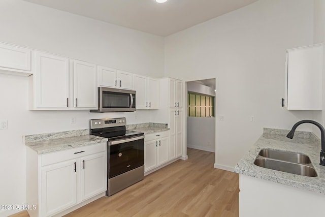 kitchen with light wood-type flooring, stainless steel appliances, white cabinetry, and sink