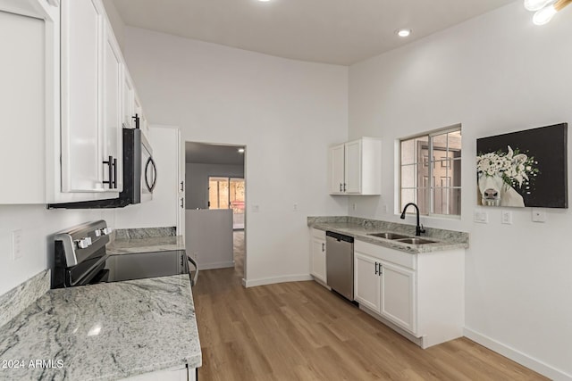 kitchen with light stone countertops, stainless steel appliances, white cabinetry, and sink