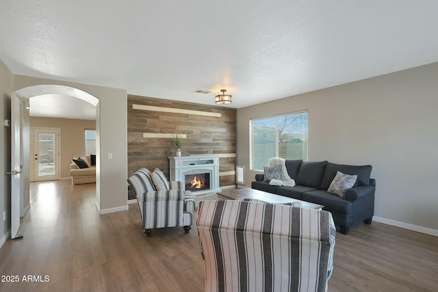 living room featuring dark hardwood / wood-style flooring, wood walls, and a textured ceiling