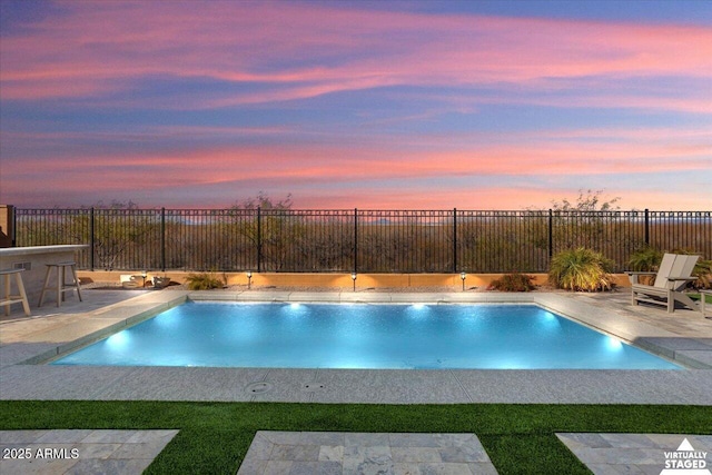 pool at dusk with exterior bar and a patio