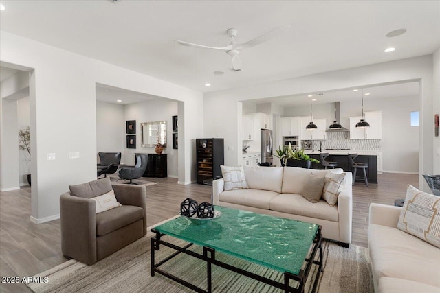 living room featuring ceiling fan, beverage cooler, and light wood-type flooring