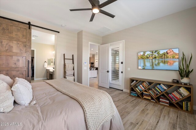 5724 E Scarlet St, Mesa, AZ 85215 - bedroom with light wood-style floors, a barn door, a ceiling fan, and connected bathroom