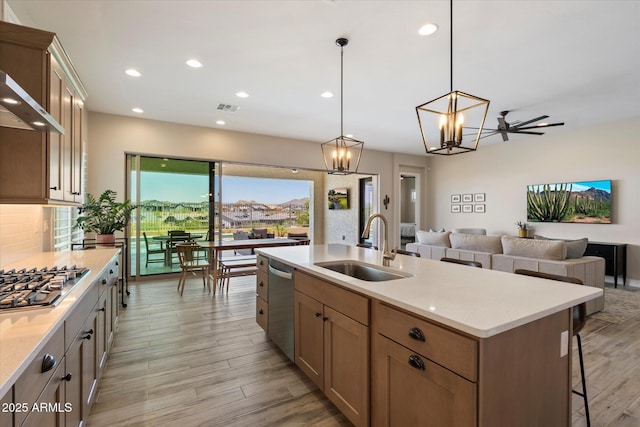 5724 E Scarlet St, Mesa, AZ 85215 - kitchen with appliances with stainless steel finishes, light wood-style floors, open floor plan, wall chimney range hood, and a kitchen island with sink