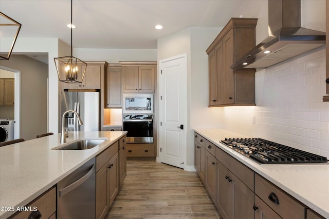 5724 E Scarlet St, Mesa, AZ 85215 - kitchen with appliances with stainless steel finishes, wall chimney exhaust hood, light wood finished floors, decorative backsplash, and pendant lighting
