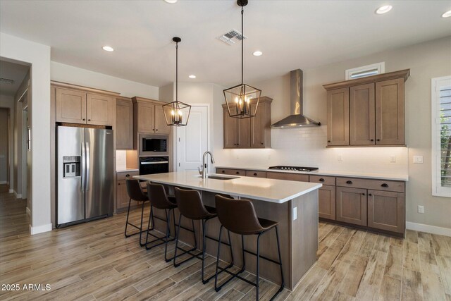 5724 E Scarlet St, Mesa, AZ 85215 - kitchen with appliances with stainless steel finishes, wall chimney range hood, light wood finished floors, tasteful backsplash, and recessed lighting