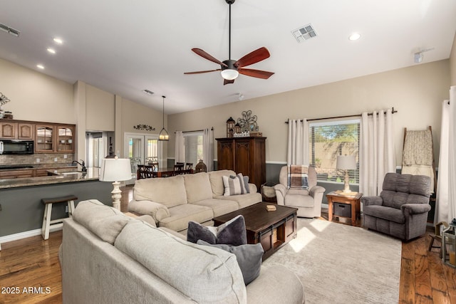 living room featuring lofted ceiling, a healthy amount of sunlight, visible vents, and dark wood finished floors