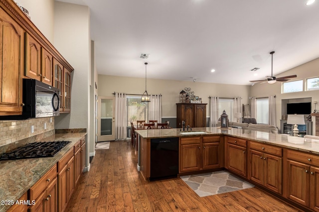 kitchen featuring black appliances, dark wood finished floors, a sink, and brown cabinetry