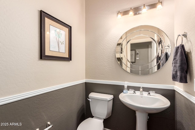 bathroom featuring a textured wall and toilet