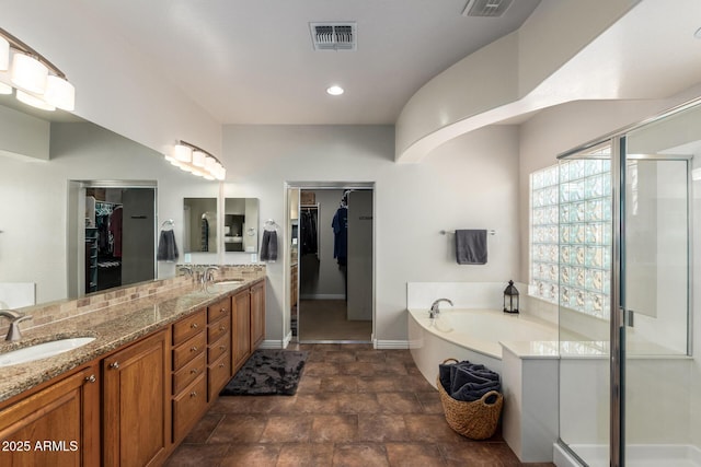 bathroom featuring a garden tub, double vanity, visible vents, a stall shower, and a sink