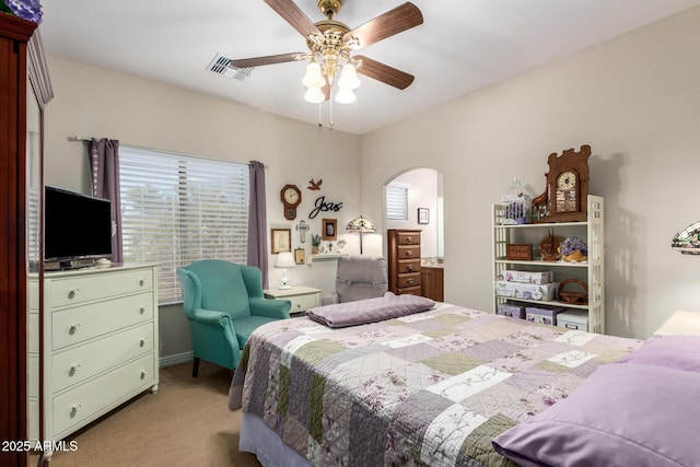 bedroom with arched walkways, a ceiling fan, visible vents, and light colored carpet