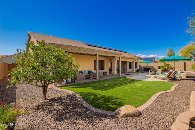 back of house featuring a fenced backyard, an outdoor hangout area, solar panels, stucco siding, and a patio area