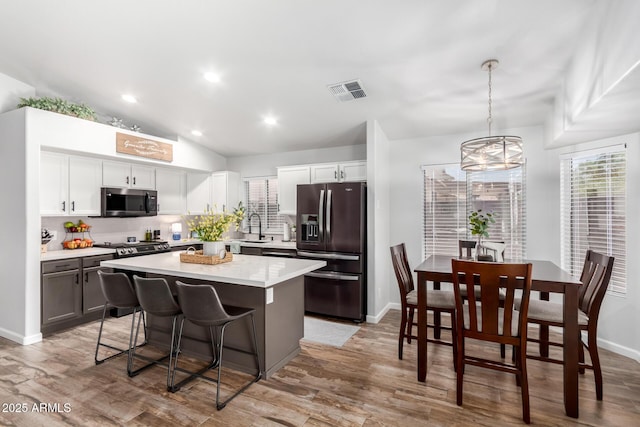 510 S Saddle St, Gilbert, AZ 85233 - kitchen featuring black refrigerator with ice dispenser, a center island, a breakfast bar, light wood-type flooring, and visible vents