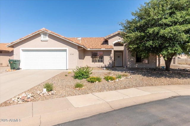 view of front of house featuring a garage, driveway, a tiled roof, and stucco siding