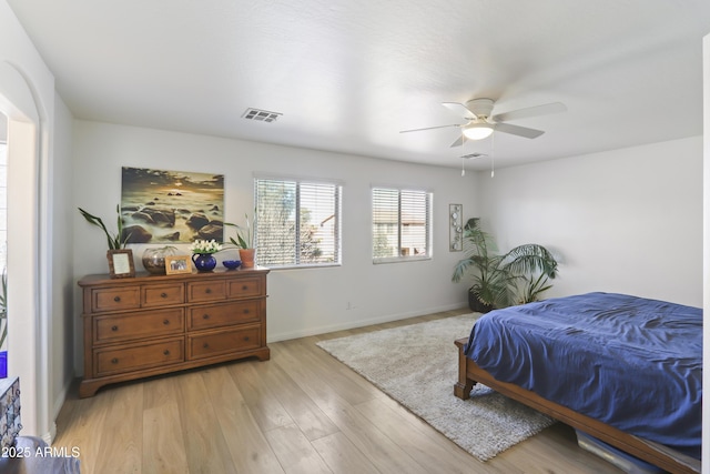 bedroom featuring light wood finished floors, baseboards, visible vents, and ceiling fan