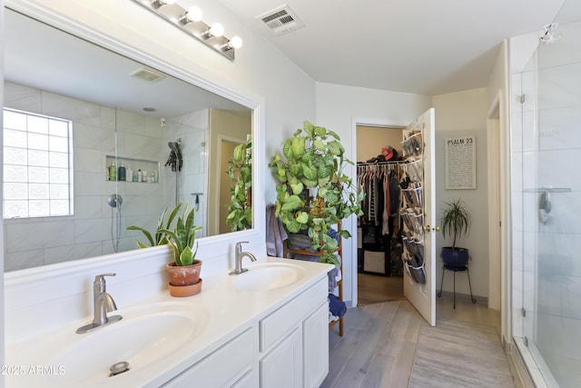 full bath featuring a stall shower, visible vents, a sink, and double vanity