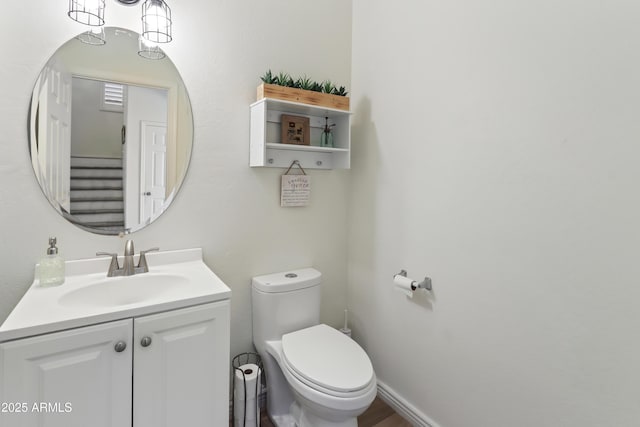 half bath featuring toilet, baseboards, and vanity